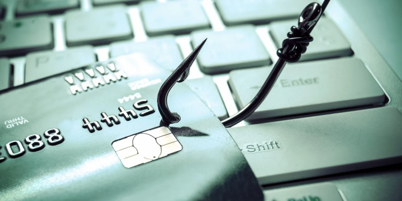 Un c&acirc;rlig agață un card de pe o tastatură, suger&acirc;nd phishing